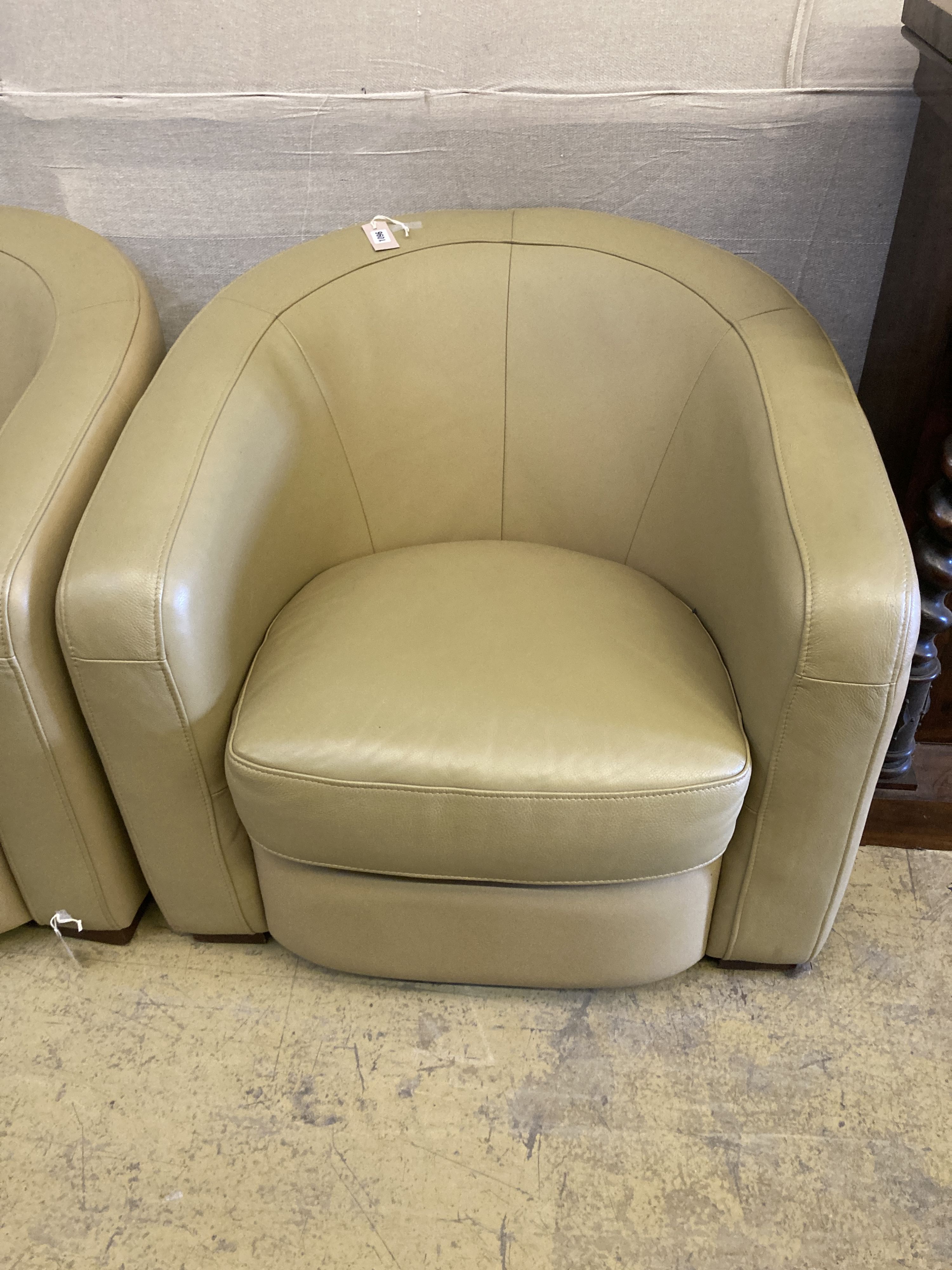A pair of tub chairs upholstered in cream leather, width 86cm, depth 75cm, height 74cm
